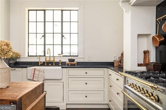 kitchen featuring stainless steel stove, sink, and white cabinets