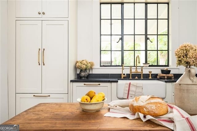 bar with white cabinetry and sink