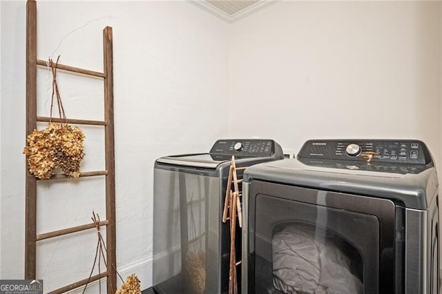 clothes washing area featuring ornamental molding and washer and dryer