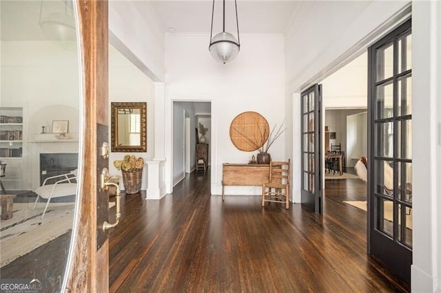 corridor with french doors, ornamental molding, and dark wood-type flooring