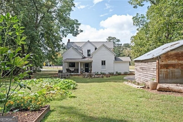 back of house with a shed, covered porch, and a lawn