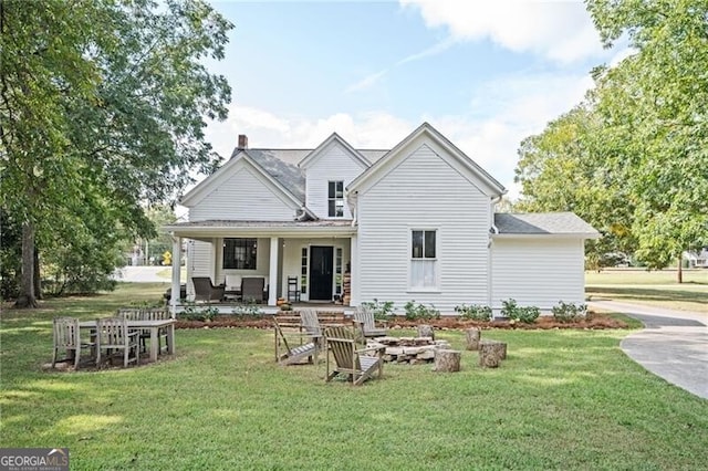 rear view of property with covered porch and a lawn