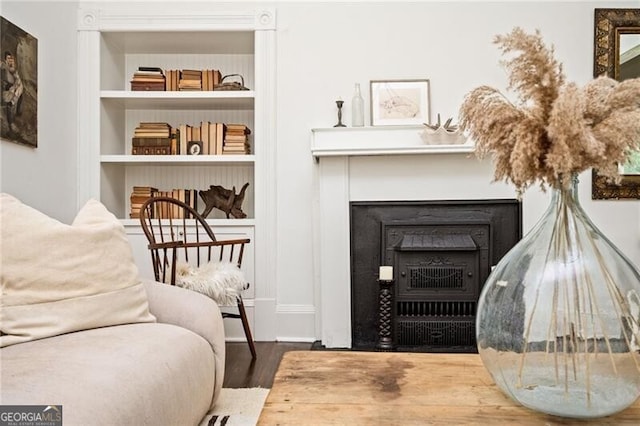 sitting room with built in shelves and wood-type flooring