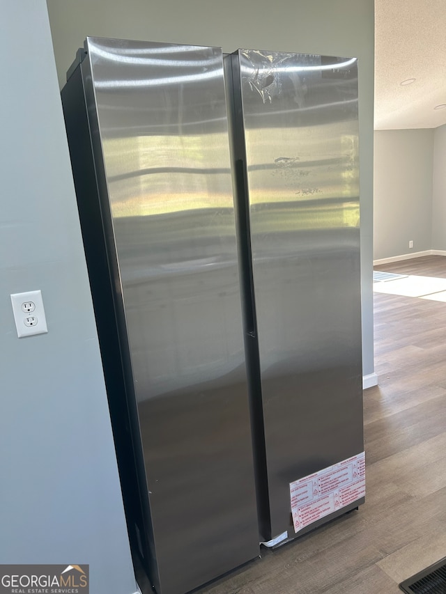 details with stainless steel refrigerator, a textured ceiling, and hardwood / wood-style flooring