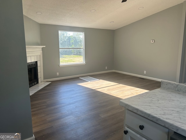 unfurnished living room with a textured ceiling, a fireplace, and dark hardwood / wood-style flooring