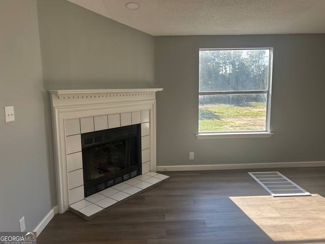 unfurnished living room with a textured ceiling, a fireplace, and dark hardwood / wood-style flooring