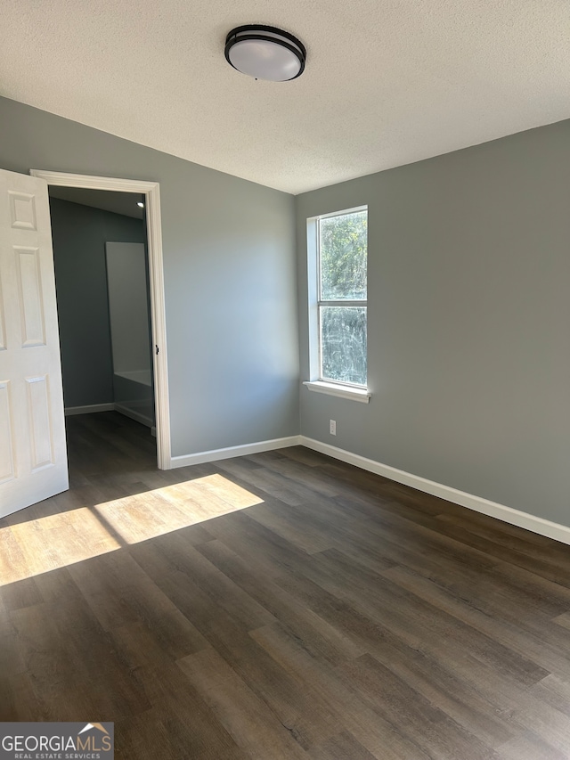 spare room with a textured ceiling and dark wood-type flooring