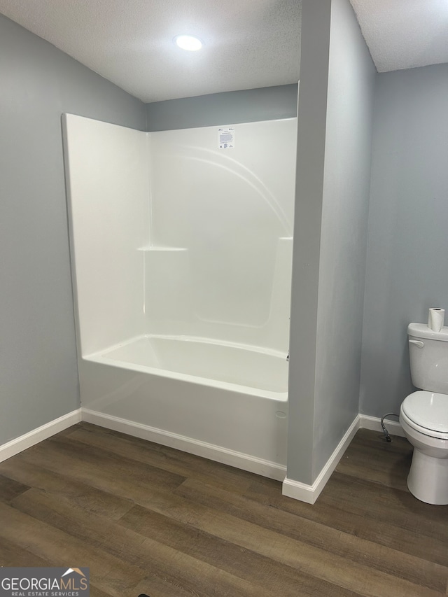 bathroom featuring a textured ceiling, wood-type flooring, toilet, and shower / washtub combination