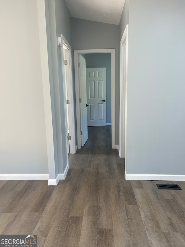 hall featuring vaulted ceiling and dark hardwood / wood-style flooring