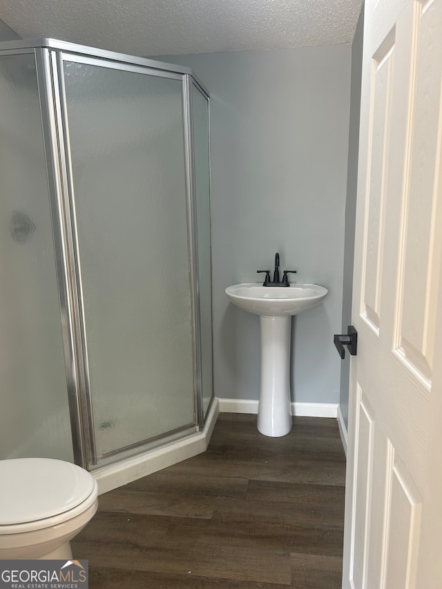 bathroom with walk in shower, toilet, a textured ceiling, and hardwood / wood-style floors