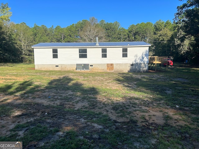 back of property with central AC unit, a deck, and a yard