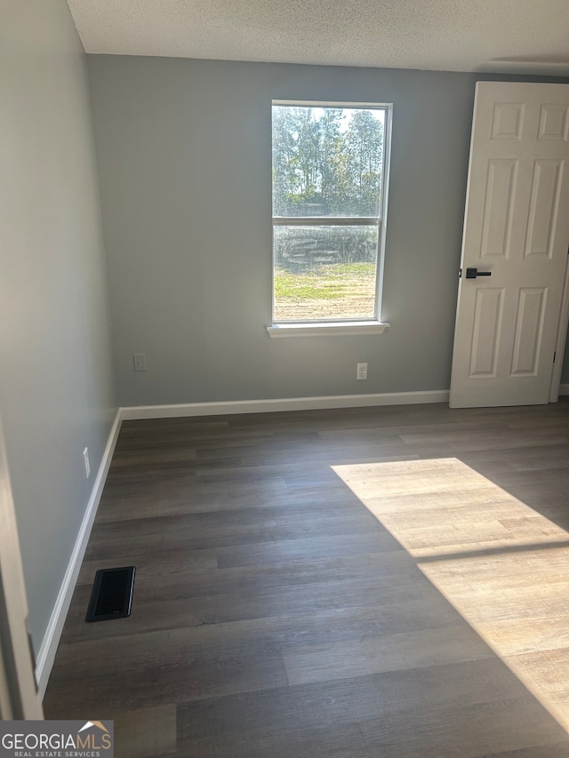 unfurnished room featuring a textured ceiling and dark hardwood / wood-style flooring