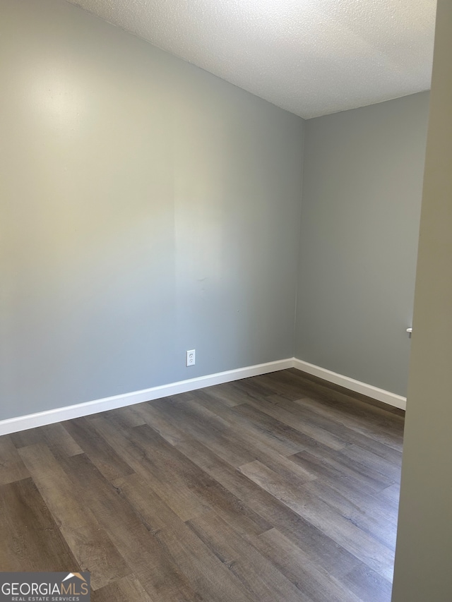 spare room featuring a textured ceiling and dark wood-type flooring