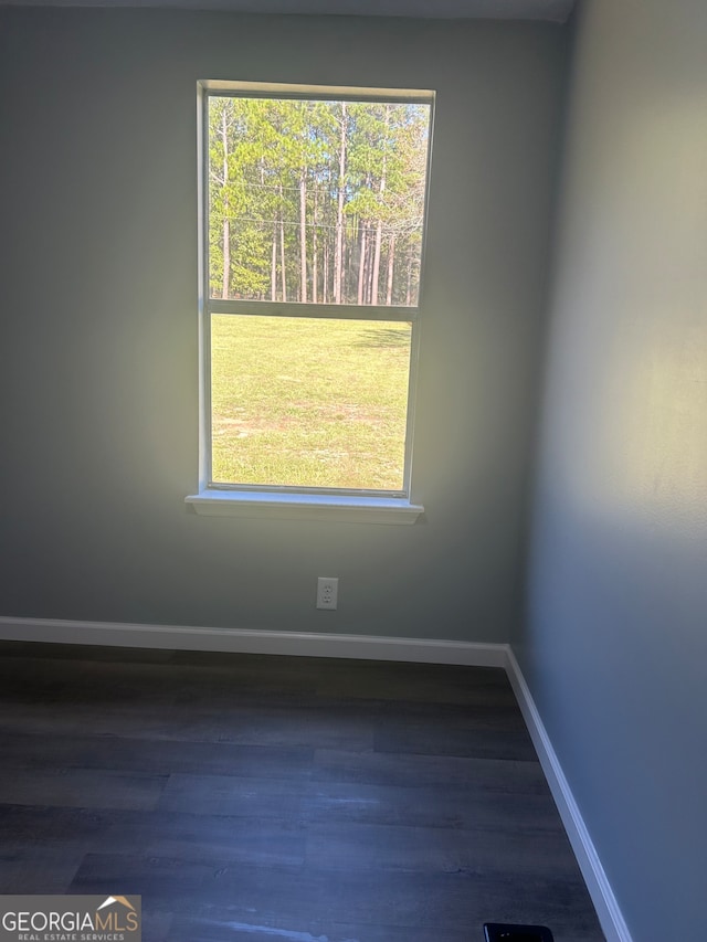 spare room with dark hardwood / wood-style flooring and a healthy amount of sunlight