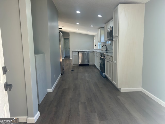 kitchen with white cabinets, stainless steel appliances, dark wood-type flooring, and vaulted ceiling