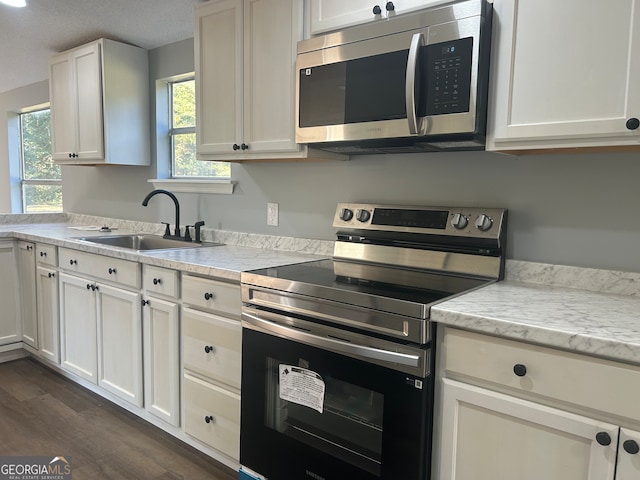 kitchen featuring a textured ceiling, sink, white cabinets, appliances with stainless steel finishes, and dark hardwood / wood-style flooring