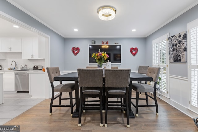 dining area featuring light hardwood / wood-style floors, sink, a healthy amount of sunlight, and ornamental molding