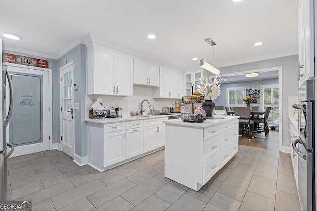 kitchen with crown molding, sink, hanging light fixtures, tasteful backsplash, and white cabinetry