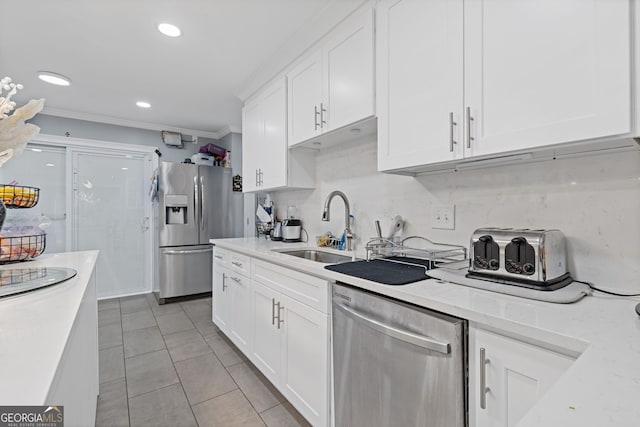 kitchen featuring white cabinetry, sink, light stone countertops, appliances with stainless steel finishes, and ornamental molding