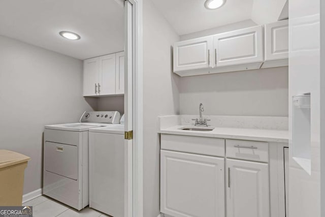 laundry area with washing machine and clothes dryer, light tile patterned flooring, cabinets, and sink