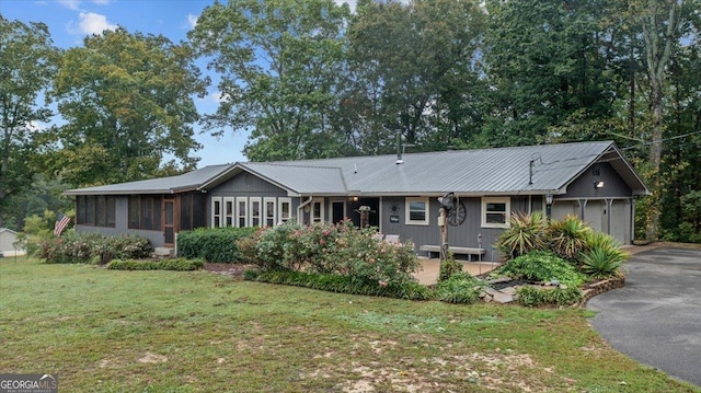 single story home featuring a front yard, a garage, and a sunroom