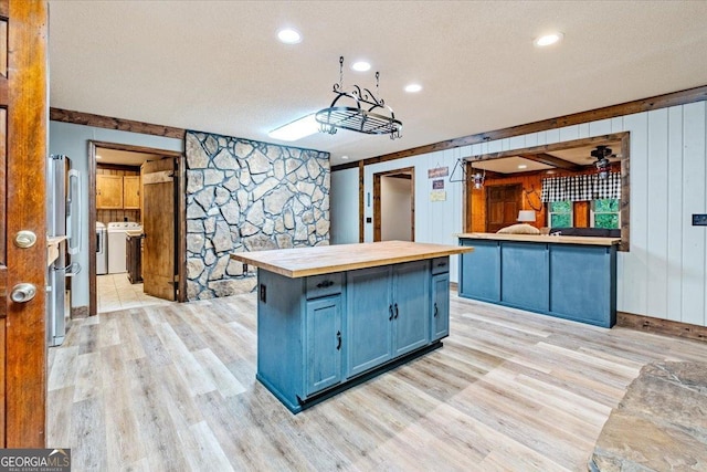 kitchen with wood counters, a center island, blue cabinets, light hardwood / wood-style flooring, and a textured ceiling