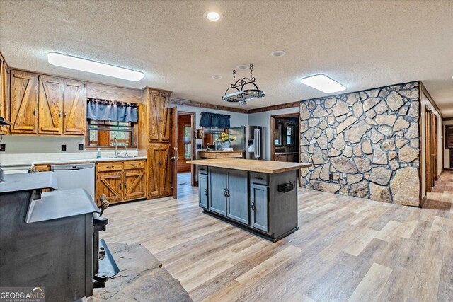 kitchen featuring white dishwasher, a kitchen island, light wood-type flooring, and a textured ceiling