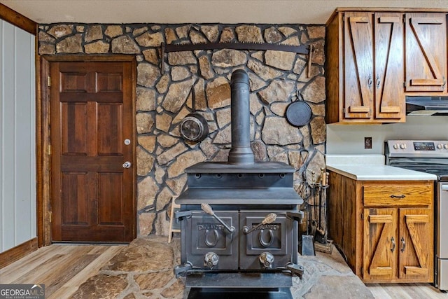 details featuring wood-type flooring, a wood stove, stainless steel electric stove, and wood walls