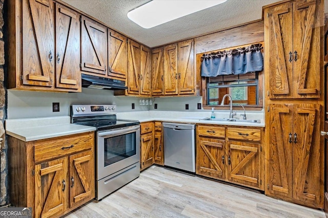 kitchen featuring a textured ceiling, sink, appliances with stainless steel finishes, and light hardwood / wood-style flooring