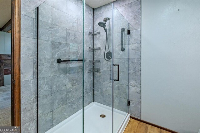 bathroom featuring hardwood / wood-style floors and a shower with shower door