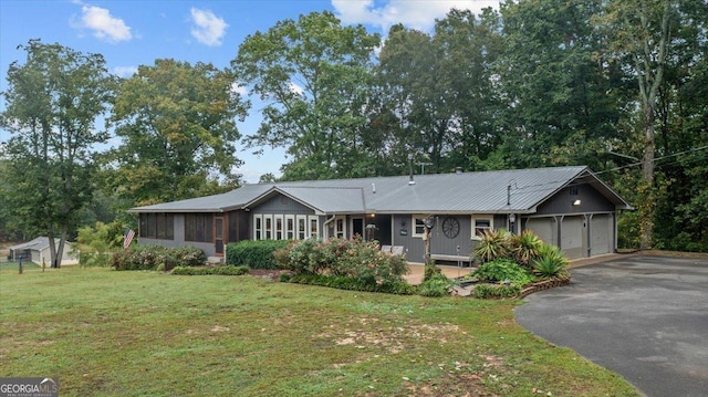 ranch-style home with a front yard, a garage, and a sunroom