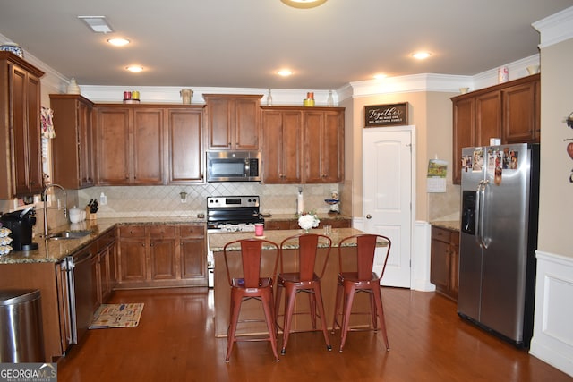 kitchen with dark wood-type flooring, a kitchen island, light stone countertops, stainless steel appliances, and sink