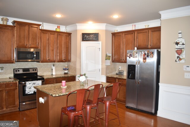 kitchen with a center island, dark hardwood / wood-style flooring, stainless steel appliances, and light stone counters