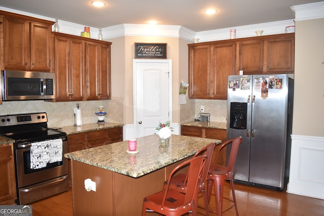 kitchen with a kitchen island, stainless steel appliances, and light stone counters