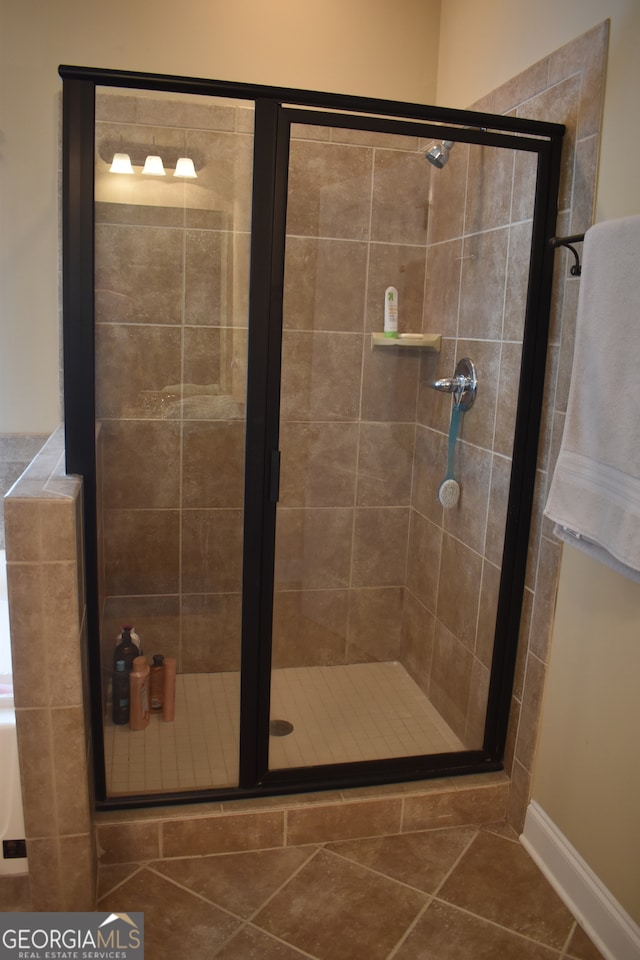 bathroom with a shower with door and tile patterned floors