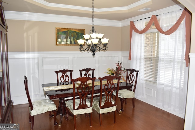 dining room featuring a raised ceiling, dark wood-type flooring, crown molding, and a chandelier