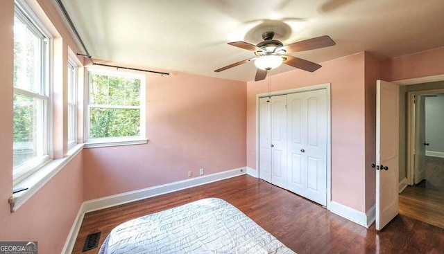 bedroom with dark hardwood / wood-style floors, ceiling fan, and a closet