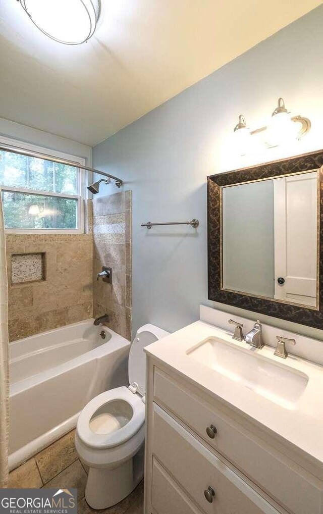 full bathroom with tiled shower / bath, vanity, and toilet