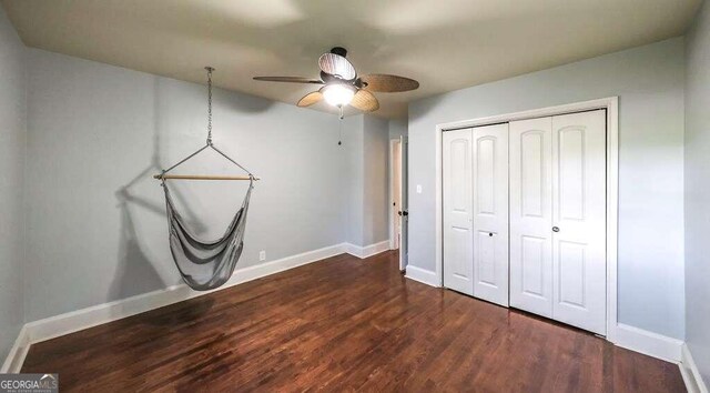 unfurnished bedroom featuring dark hardwood / wood-style flooring, ceiling fan, and a closet