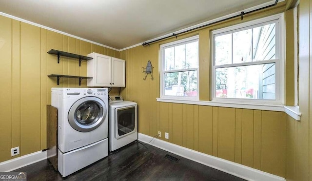 clothes washing area with cabinets, dark hardwood / wood-style flooring, wood walls, crown molding, and washing machine and dryer