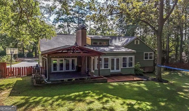 rear view of property with a lawn, a trampoline, and french doors