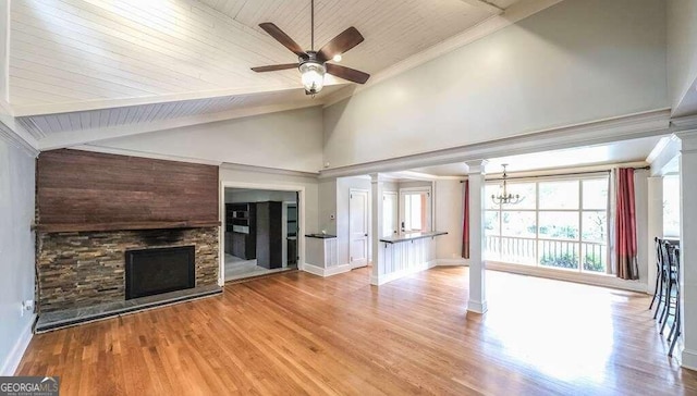 unfurnished living room with light hardwood / wood-style floors, wood ceiling, ceiling fan with notable chandelier, a stone fireplace, and decorative columns