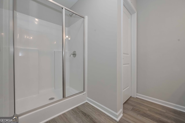 bathroom featuring wood-type flooring and a shower with shower door