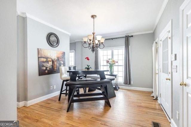 dining area with light hardwood / wood-style flooring, an inviting chandelier, and crown molding