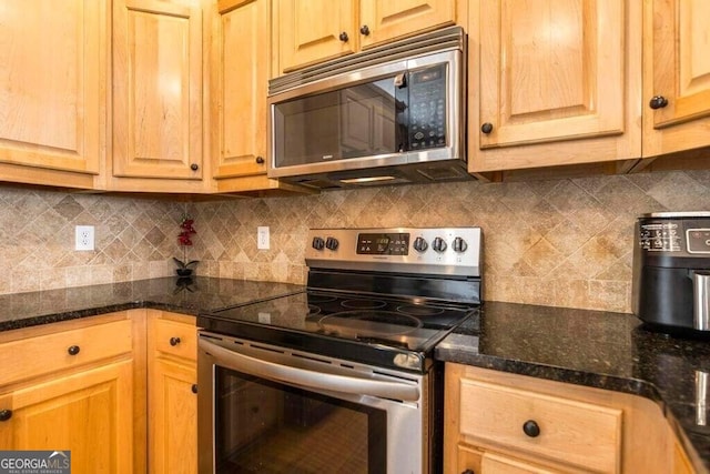 kitchen with dark stone countertops, stainless steel appliances, and decorative backsplash