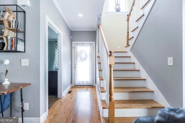 entryway with wood-type flooring and crown molding