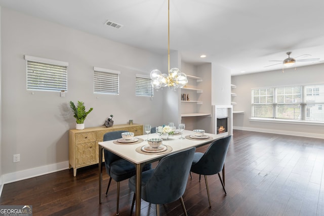 dining room with ceiling fan with notable chandelier and dark hardwood / wood-style flooring