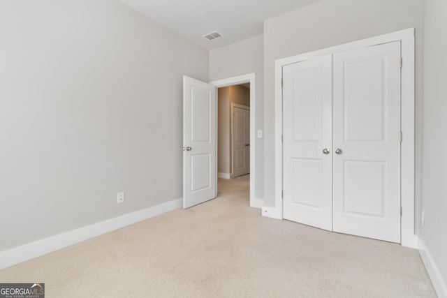 unfurnished bedroom with light carpet and a closet