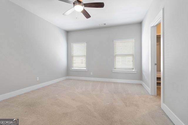 carpeted empty room with ceiling fan and plenty of natural light