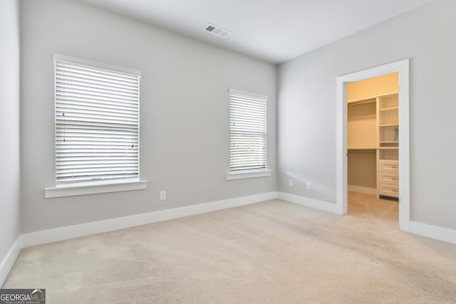 unfurnished bedroom with light carpet, a closet, and a spacious closet